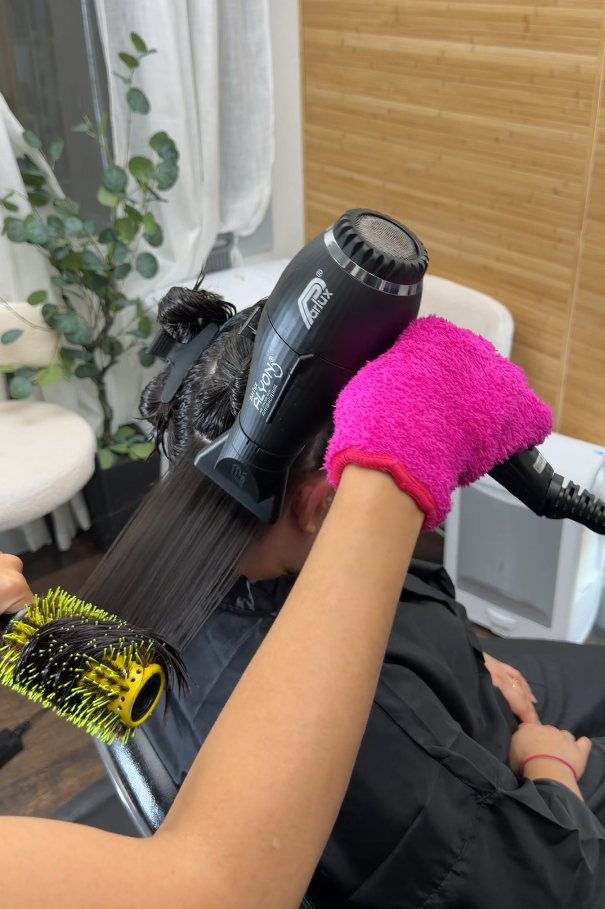 Blow-drying straight hair with a round brush during a service